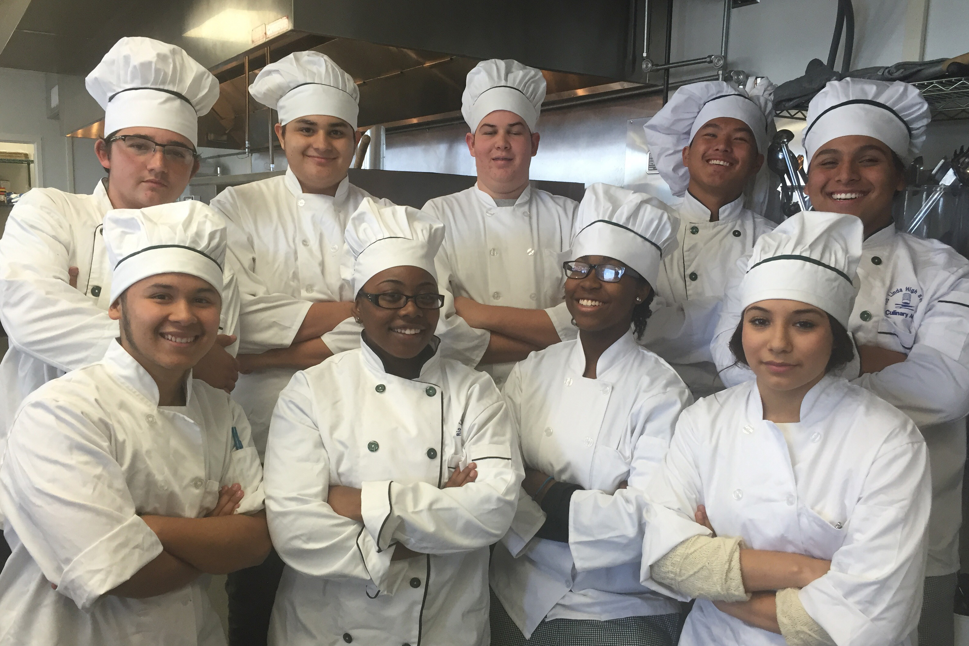 Culinary students dressed up in chef outfits in the kitchen standing together in a group